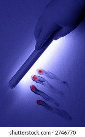 CSI Crime Scene Investigator Technician Hand Holding UV Black Light Wand To Reveal Bloody Finger Print Smear In A Crime Scene (fictitious Representation)