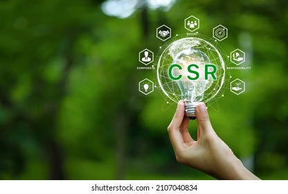 CSR Icon Concept In The Hand For Business And Organization, Corporate Social Responsibility And Giving Back To The Community On A Green Nature Background.