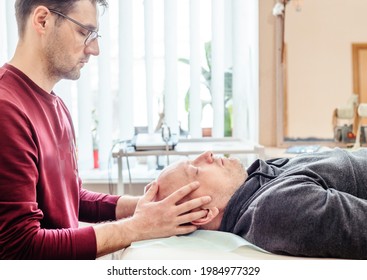 CST therapist uses gentle touch to palpate the synarthrodial joints of the cranium of a male patient, osteopathy and manual therapy