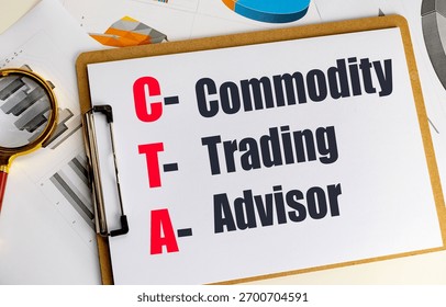 Cta acronym for commodity trading advisor written on clipboard with financial documents and magnifying glass . 