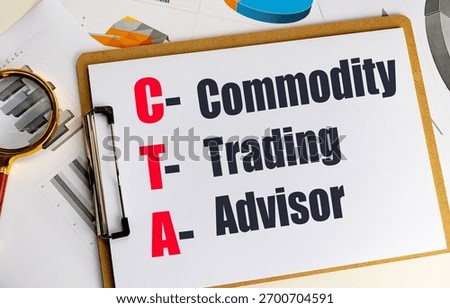 Cta acronym for commodity trading advisor written on clipboard with financial documents and magnifying glass . 