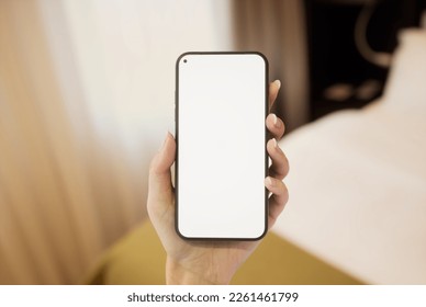 CU 20s Caucasian female holding a phone in a left hand, hotel room bed in bg - Shutterstock ID 2261461799