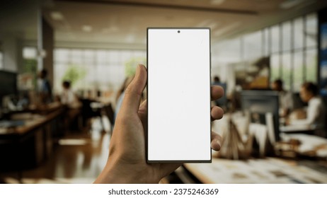 CU 30s Caucasian male holding a generic smart phone in vertical orientation, bright open space office in background, green screen chroma key - Powered by Shutterstock