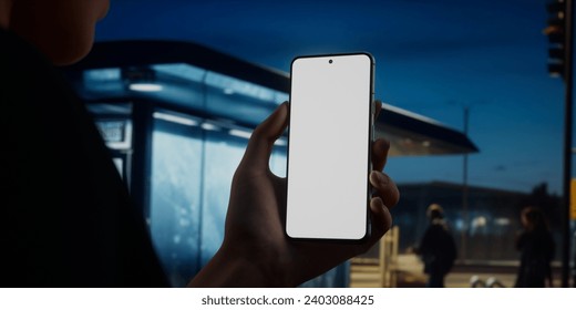 CU Caucasian female using her phone in the street at night near bus stop. Blank phone screen ticket, maps, travel, taxi application mockup - Powered by Shutterstock