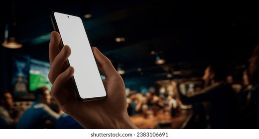 CU Caucasian man using phone inside a sports bar, online betting, bookmaker app application blank screen phone mock-up - Powered by Shutterstock