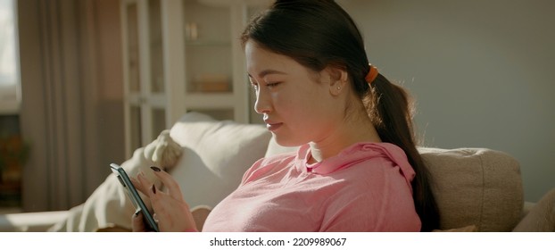 CU Portrait Of Asian Korean Female Checking Her Phone At Home Early In The Morning. Natural Cinematic Light