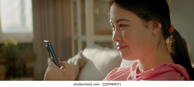 CU Portrait Of Asian Korean Female Checking Her Phone At Home Early In The Morning. Natural Cinematic Light