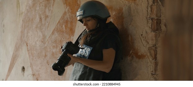 CU Portrait of Caucasian female war journalist wearing protective helmet and bulletproof vest gear taking photos under fire