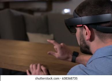 CU young adult Caucasian male using holographic augmented reality glasses in trendy office. Future business concept