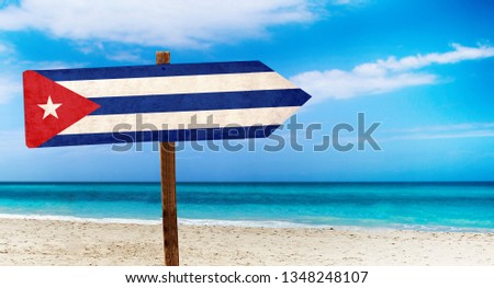 Cuba flag on wooden table sign on beach background. It is summer sign of Cuba.