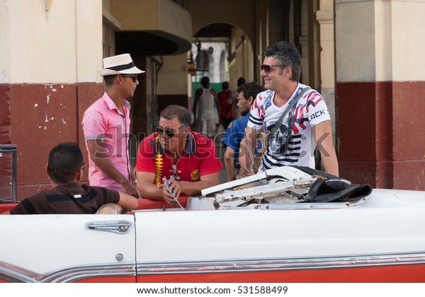 Cuba, Havana. Men hanging out near a vintage\
car. 2016-04-02