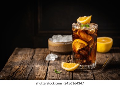 Cuba Libre in a glass with brown rum, cola, mint and lemon on dark background. Cuba Libre or long island iced tea cocktail with strong drinks