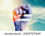 Cuba national flag fist raise in the sky. The hand with flag raise in beautiful soft sky. Cuba national flag for independence day.