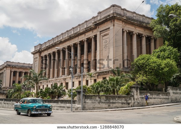 Cuban cars, Green classic iconic car on road passing\
old historical building in Havana or Habana in sunny day under\
beautiful blue sky with copy space. Colorful classic vehicles,\
landmarks in Cuba