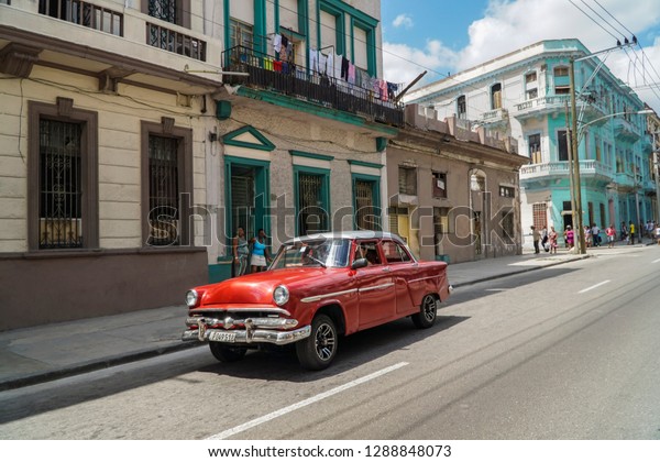 Cuban\
cars, Red classic iconic caron road passing old building or houses\
in Havana or Habana in sunny day under beautiful blue sky with copy\
space. Colorful classic vehicles, landmarks in\
Cuba