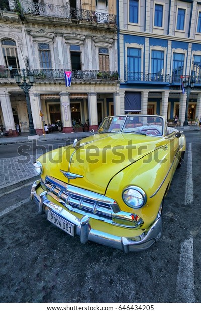 Cuban cars, Yellow classic iconic car parked on\
road in Havana or Habana, Cuba. Colorful vehicles, one of the\
landmarks of Cuba in\
Havana