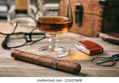 Cuban cigar and a glass of cognac brandy on wooden background, closeup view with details - Powered by Shutterstock