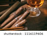 Cuban cigars in a wooden box, blur glass of cognac brandy, closeup view with details, copy space
