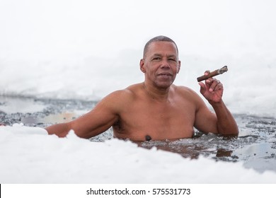 Cuban man swims in an ice hole in winter smoking a cigar