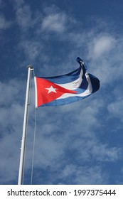 Cuban national flag in the wind on a sunny day with clouds in the background
