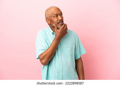 Cuban senior isolated on pink background having doubts - Powered by Shutterstock