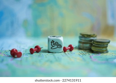 Cube with an airplane and coins on the background of the world map. The concept is travel.
