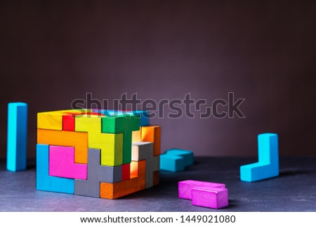 Cube of multi-colored wooden shapes. Concept of decision making process, creative, logical thinking. Choose correct answer. Logical tasks. Conundrum, find the missing piece of the proposed.