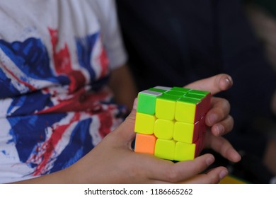 Cube puzzle with multi-colored faces in the hands of a child of school age