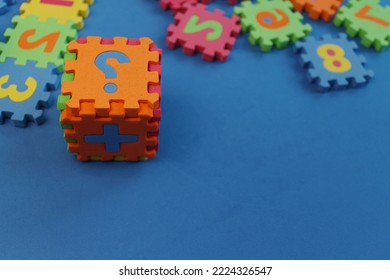 a cube of soft puzzles, a question mark, scattered puzzles on a blue table - Shutterstock ID 2224326547