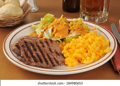 A Cube Steak Dinner With Macaroni And Cheese And A Salad