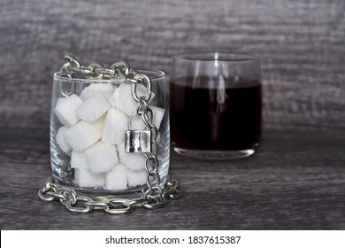 Cube Sugar In The Clear Glass Locked By The Metal Chain And Padlock With The Glass Of Black Coffee Background