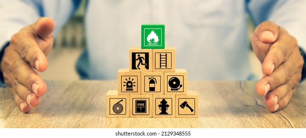 Cube wooden toy block stack in pyramid with hand protect with fire icon and door exit sing or fire escape with prevent and fire extinguisher and emergency protection symbol for safety and rescue.