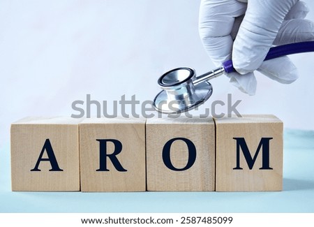 Cubes with the abbreviation AROM (Active range of motion) in the hand of a doctor. Medical concept