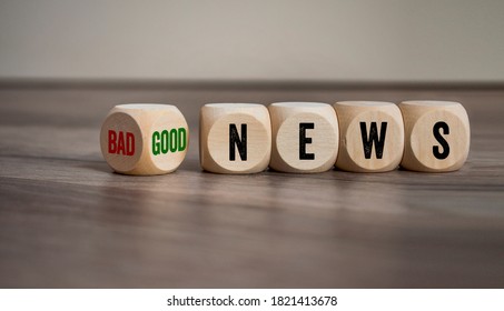 Cubes and dice with bad news and good news on wooden background
