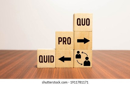 Cubes and dice with business message quid pro quo on wooden background.