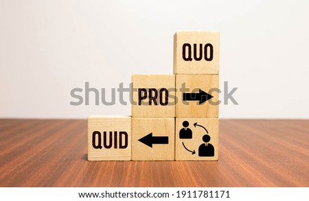 Cubes and dice with business message quid pro quo on wooden background.