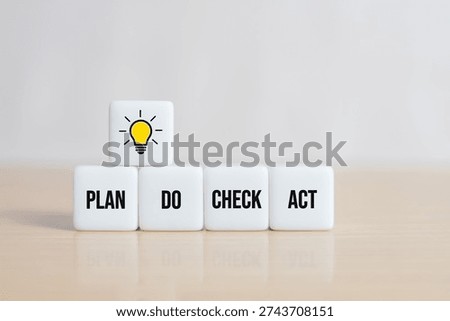 Cubes dice with lightbulb and PDCA concept. Plan Do Check Act on wooden background