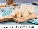 Cubes of fresh organic tofu cheese with rosemary on a board close-up