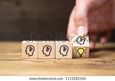 cubes with head symbols and hand that flips one revealing an idea