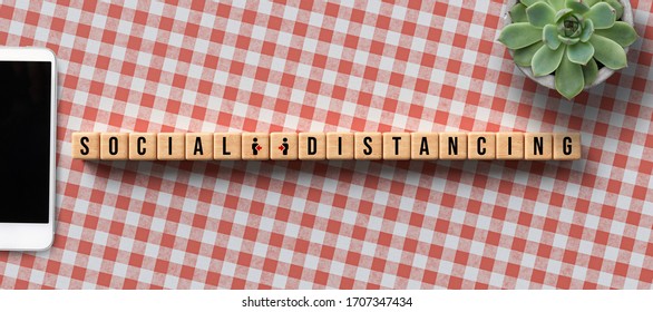 cubes with message SOCIAL DISTANCING and computer equipment on kitchen table background - Powered by Shutterstock - Get 15% off with code: PIKWIZARD15