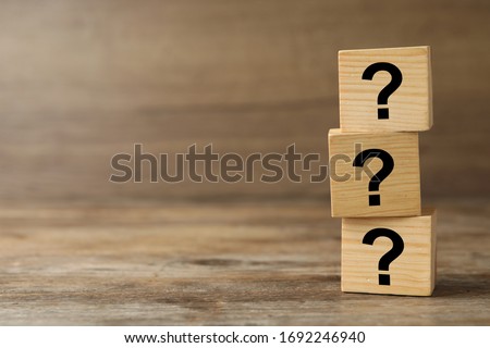 Cubes with question marks on wooden background, closeup. Space for text