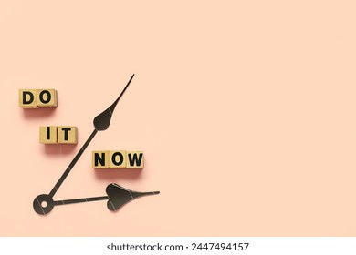 Cubes with text DO IT NOW and clock hands on beige background. Top view