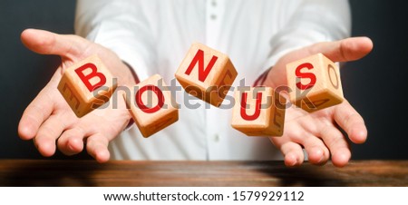 Cubes thrown by a man make up the word BONUS. Receive bonuses, rewards and preferences. Salary increase, wage premium for holidays. Getting benefits and extra points. Promotional gift. rising