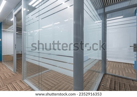 Cubicle office with glass partitions and doors. Floor covering with a beautiful geometric 
pattern.