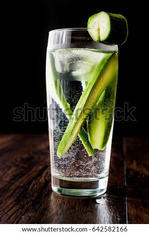 Cucumber Cocktail with vodka and tonic on dark wooden surface.
