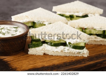 Cucumber cream cheese sandwiches closeup on the wooden board on the table. Horizontal
