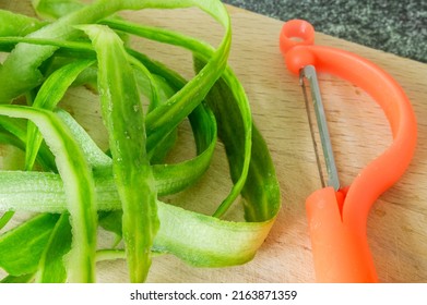 Cucumber Peel And Vegetable Peeler On A Wooden Board