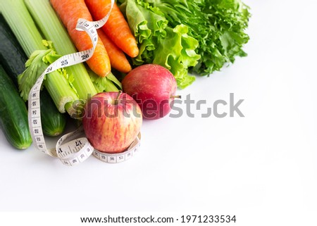 Cucumbers, celery, carrots, green lettuse, red apples and measure tape isolated on a white background. Fruit and vegetables. Diet, wellness and weight loss concept. Healthy lifestyle. Good nutrition