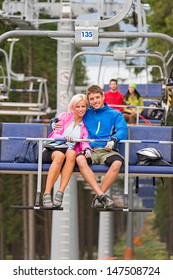 Cuddling Young Couple Sitting On Chair Lift In The Pinewood