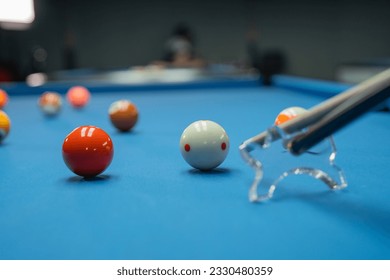 a cue stick poking the white ball using the bridge on the billiard game
